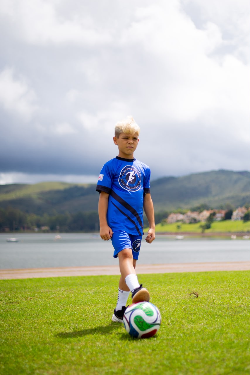 Aluno com bola de futebol em treino ao ar livre